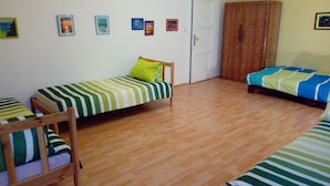 Une chambre avec deux lits simples, du linge de lit à rayures, une armoire en bois et une porte.
