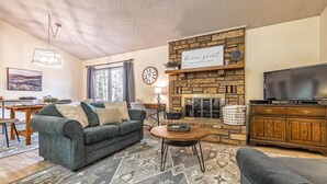 A cozy living room with a stone fireplace, a television, and a comfortable seating area. - Golf Lover's Getaway! Cozy 2BR/2BA Townhome, Walk to DeSoto Golf Club! (Hot Springs)