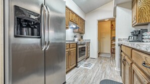 A kitchen with stainless steel appliances, wooden cabinets, and a marble countertop. - Golf Lover's Getaway! Cozy 2BR/2BA Townhome, Walk to DeSoto Golf Club! (Hot Springs)