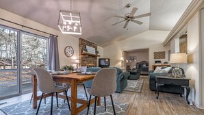 A spacious living room with a wooden dining table, two chairs, a sofa, and a ceiling fan. - Golf Lover's Getaway! Cozy 2BR/2BA Townhome, Walk to DeSoto Golf Club! (Hot Springs)