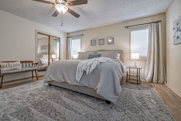 A bedroom with a bed, a bedside table, a mirror, and a ceiling fan. - Golf Lover's Getaway! Cozy 2BR/2BA Townhome, Walk to DeSoto Golf Club! (Hot Springs)