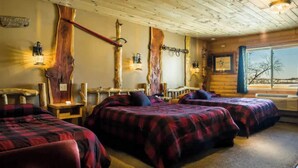 Une chambre de style cabane avec deux lits, des murs en bois et une grande fenêtre donnant sur un paysage agréable.
