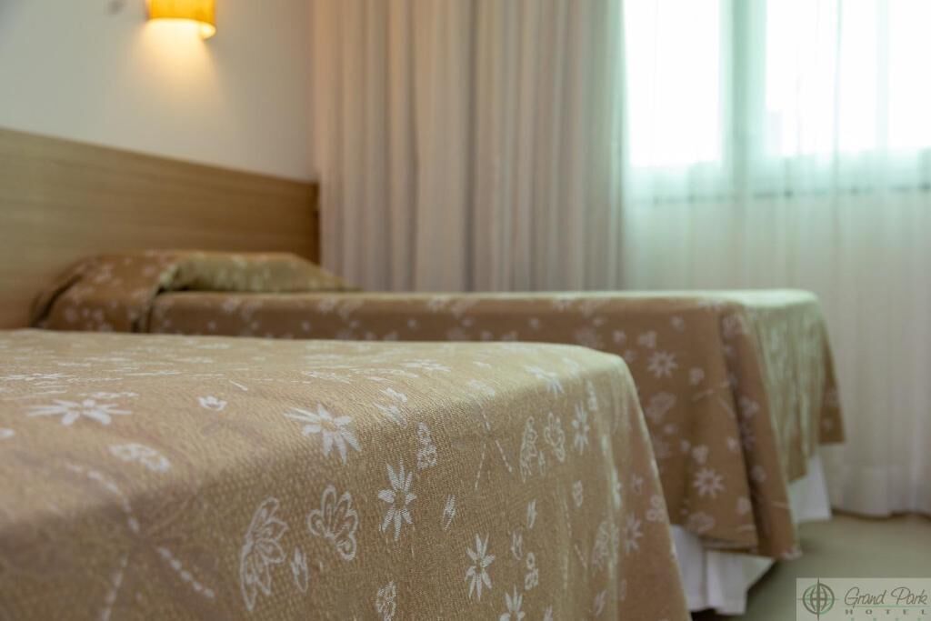 A hotel room with two beds, each covered with a floral-patterned bedspread.