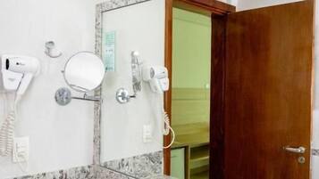 Un baño con lavamanos de encimera de granito, un espejo y dos secadores de pelo fijados en la pared.