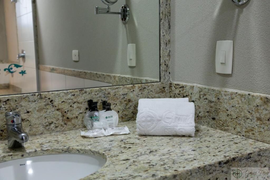 Une salle de bain avec un comptoir en granit, un lavabo, un miroir et des articles de toilette.