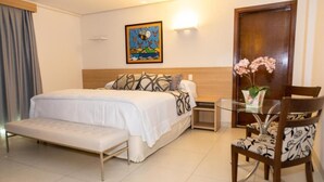 A hotel room with a bed, bedside table, chair, and a decorative vase. - Grand Park Hotel (Campo Grande)