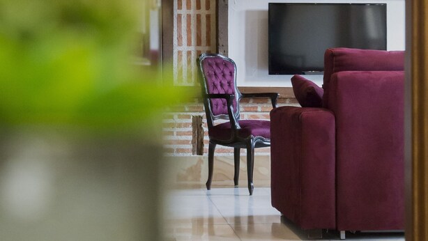 A living room with a TV, a purple armchair, and a red sofa.