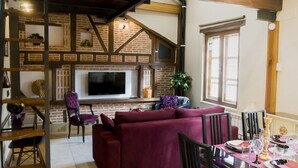 A living room with a fireplace, a TV, a sofa, and a dining table set for two.