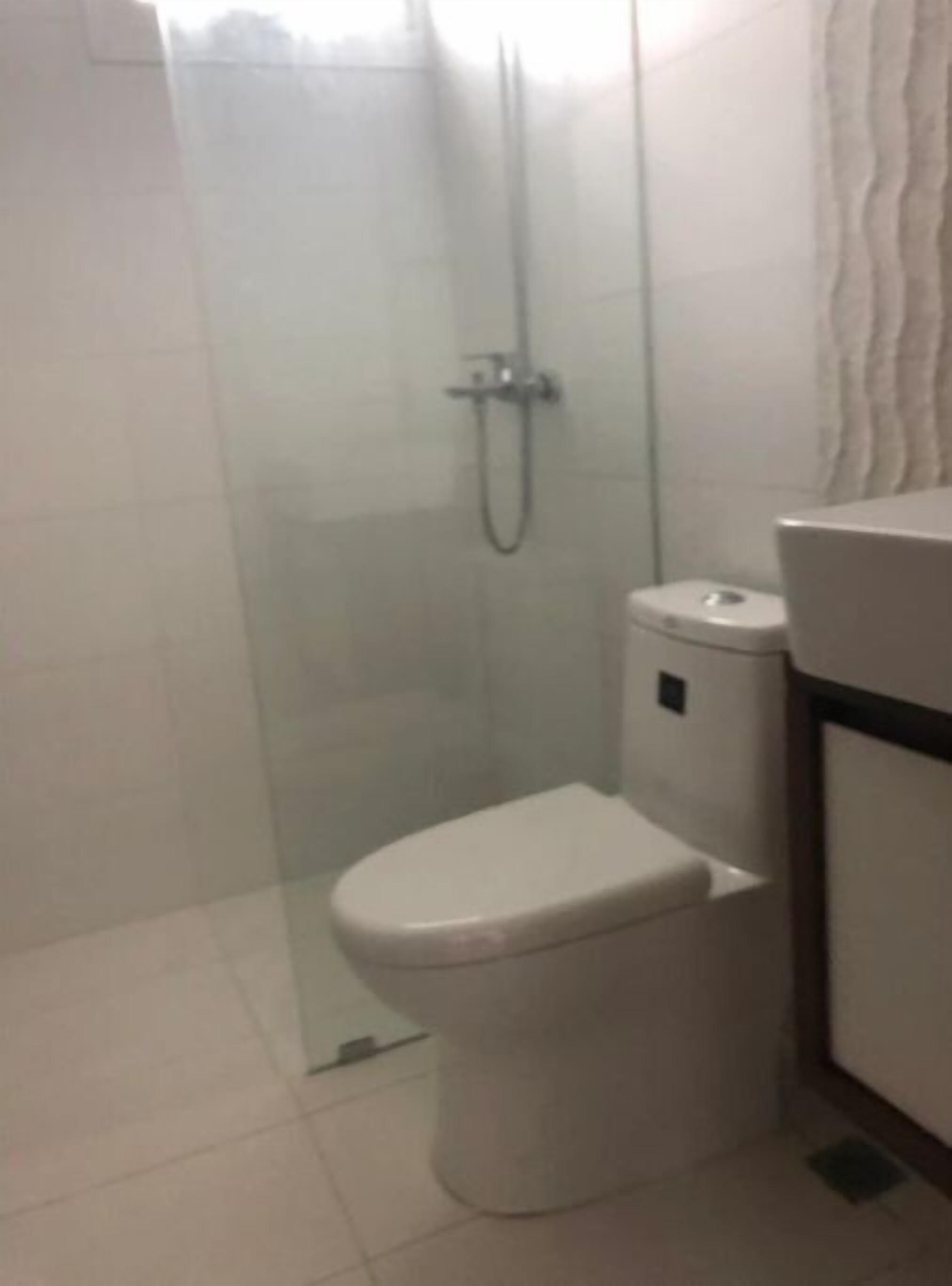A small, enclosed shower area with a glass door, a toilet, and a sink.