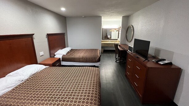 A hotel room with two beds, a desk with a computer, a TV, and a mirror. - Scottish Inns Jonesboro AR  (Jonesboro)
