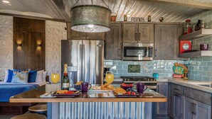 A modern kitchen with a central island, bar stools, a microwave, and a sign that reads "FRIENDS".