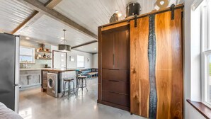 A spacious kitchen with a central island, bar stools, and a large wooden sliding door.