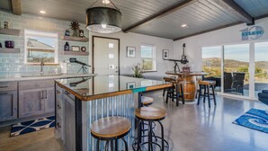 A modern kitchen with a large island, bar stools, and a view of the desert through large windows.