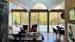 A spacious room with large windows, a pool, and a ceiling fan.
