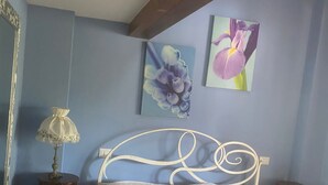 Une chambre à coucher comprenant un lit, une table de chevet, une lampe et deux tableaux accrochés au mur.
