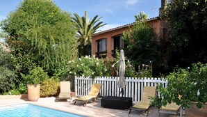 A swimming pool with lounge chairs and a white picket fence. - Locations de Vacances (Porticcio)