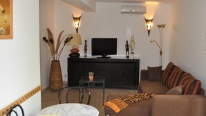 A living room with a sofa, TV, and a dining table. - Locations de Vacances (Porticcio)