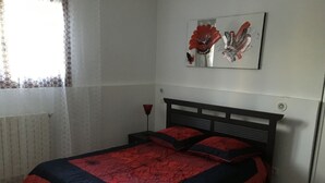 A bedroom with a bed, a nightstand, a lamp, and a wall-mounted artwork. - Locations de Vacances (Porticcio)