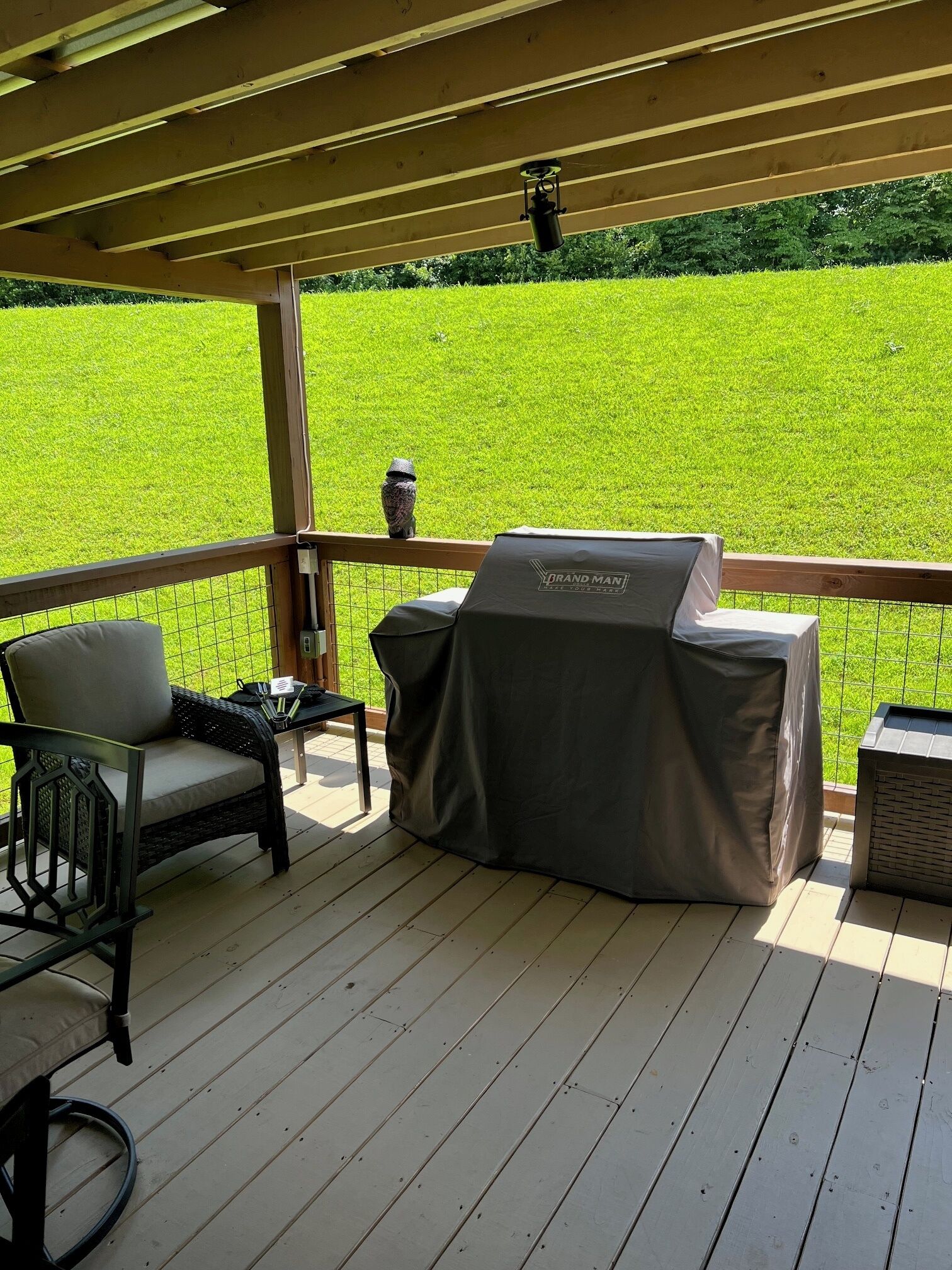 A covered outdoor deck with a grill, a chair, and a table.