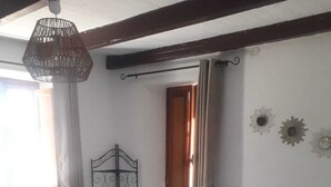Ein Schlafzimmer mit Bett, einer Pendelleuchte, einem Fenster mit Vorhängen und Wanddekorationen.