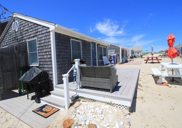 A row of beach cottages with outdoor seating and a barbecue area.