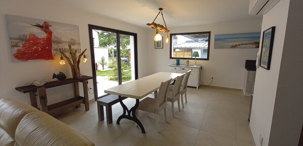 A dining area with a table and chairs, a bench, and a painting on the wall. - BEACH DREAM (Hauteville-sur-Mer)