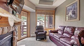 Relax in the living room with a fireplace, sofa, and armchair, taking in the views of the surrounding landscape.