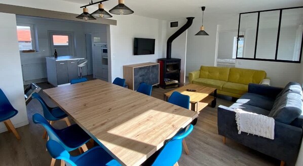 Relax in this stylish living space with a central dining table, comfortable seating areas, and a fireplace.