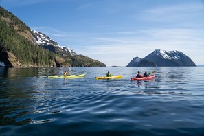 Three kayaks on calm water with mountains in the background.