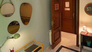 Un pasillo con una puerta de madera, un espejo, una lámpara y un cartel en la pared.