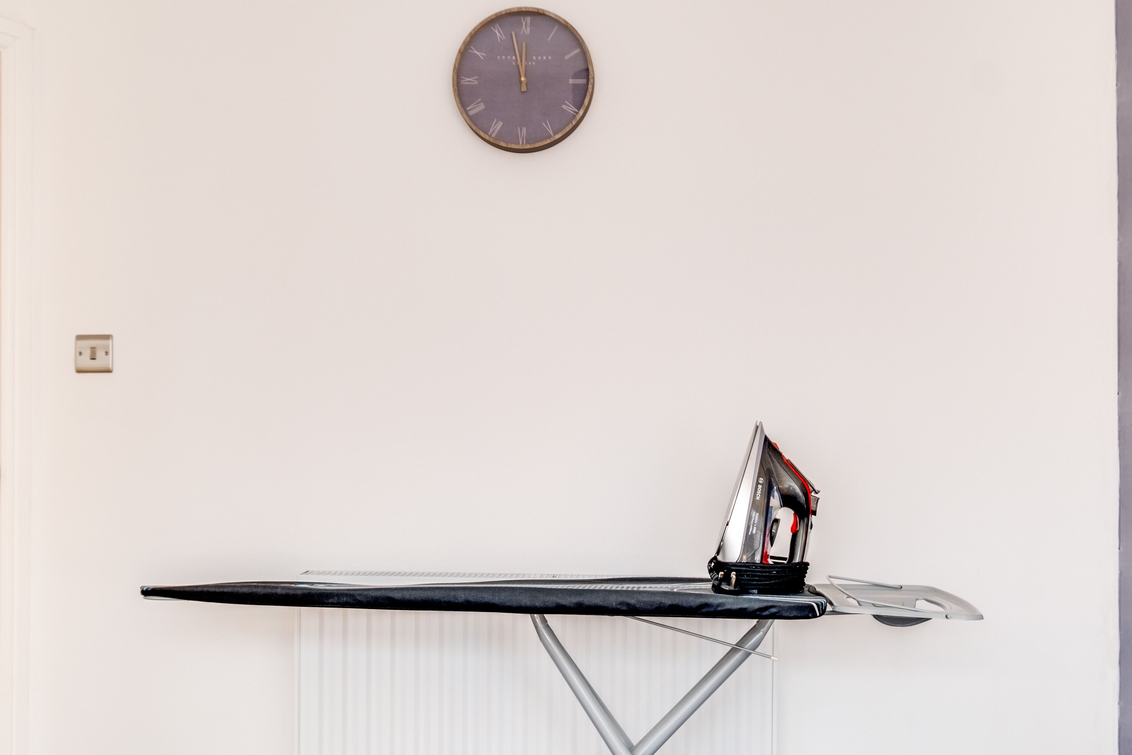 Un reloj de pared y una tabla de planchar con plancha.