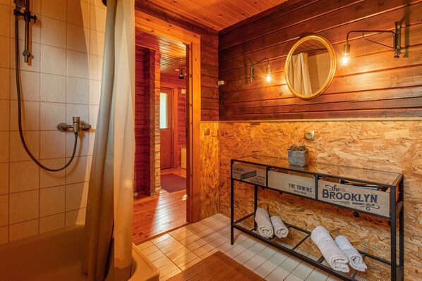 Une salle de bain avec une douche, un mur en bois, un miroir et un porte-serviettes.