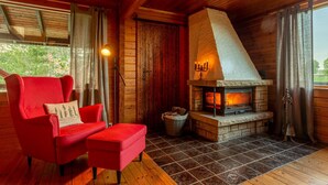 A cozy room with a red chair, a fireplace, and a view of the outdoors.