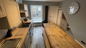 Une cuisine compacte avec une table en bois, un four encastré et une horloge au mur.