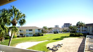 A resort with a sandy beach, palm trees, and a clear blue sky. - Cozy Condo at Sandpiper Cove/  pool and golf view (Destin)