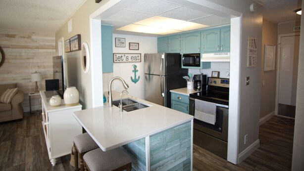 A compact kitchen with teal cabinets, a white countertop, and a built-in sink. - Cozy Condo at Sandpiper Cove/  pool and golf view (Destin)
