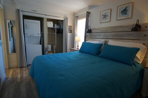 Ein Schlafzimmer mit Bett, Kleiderschrank, Nachttisch und Lampe.