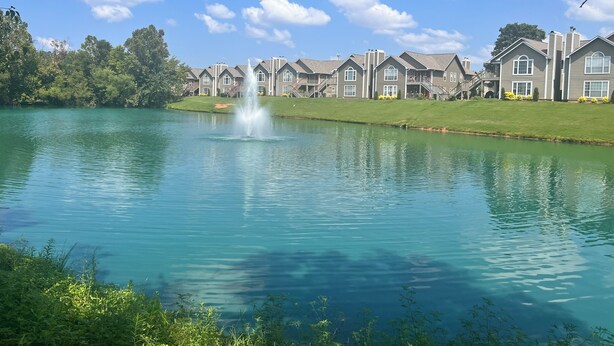 A lake with a fountain, surrounded by a row of houses with a well-maintained lawn and a clear blue sky. - Executive Condo - Gigabit Wi-Fi - Near Redstone Arsenal - 2 beds-2 baths (Madison)