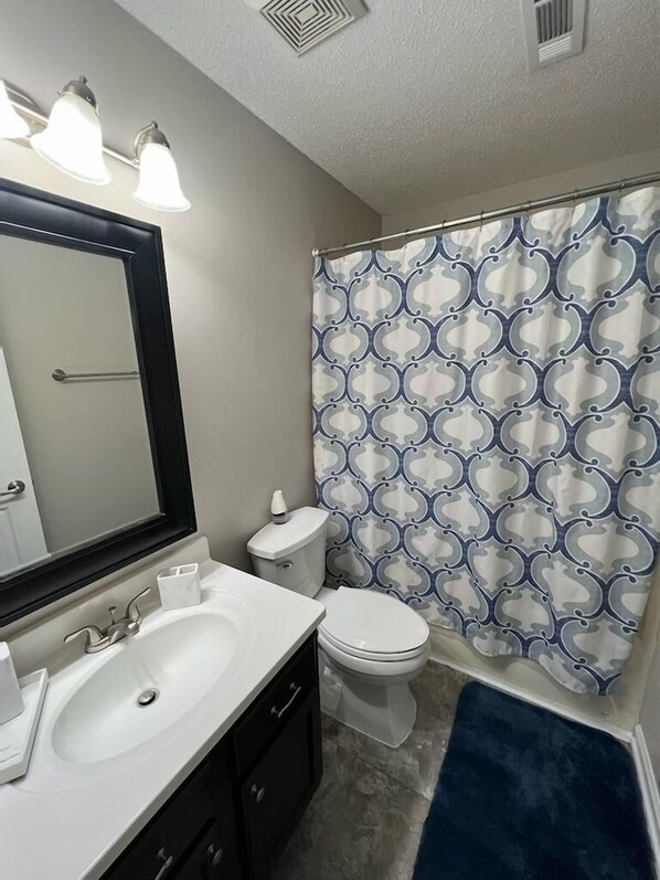 A bathroom with a white sink, a mirror, a toilet, and a shower curtain with a geometric pattern. - Executive Condo - Gigabit Wi-Fi - Near Redstone Arsenal - 2 beds-2 baths (Madison)