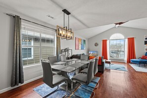 A dining area with a glass table and chairs, a chandelier, and a view of the outdoors. - Executive Condo - Gigabit Wi-Fi - Near Redstone Arsenal - 2 beds-2 baths (Madison)