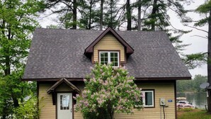 A two-story house with a gabled roof, a front door, and a small porch. - Lakefront Muskoka Beautiful Cottage  (Gravenhurst)