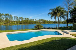 A swimming pool with a view of a lake and trees.
