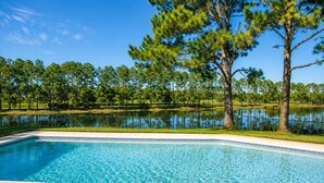 A swimming pool with clear blue water, surrounded by a grassy area and trees. - SWISS 24 - Lake Stephanie (Clermont)