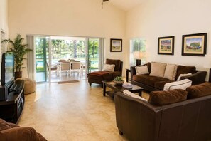 A living room with a sofa, coffee table, TV, and a dining area with a table and chairs.