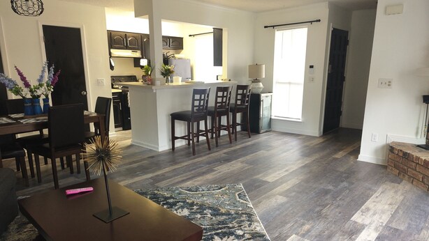 A spacious living room with a dark wooden coffee table, a patterned rug, and a dining area with chairs. - Charming NOLA Condo (New Orleans)