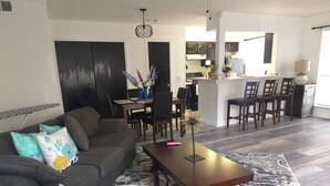 A living room with a sofa, coffee table, and a dining area with chairs and a table. - Charming NOLA Condo (New Orleans)