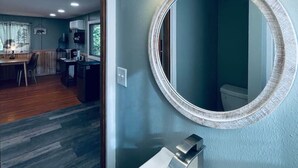 A bathroom with a round mirror, a white sink, and two wall-mounted lights. - Romantic Cabin, Mnt View, Perfect Location❤️ (Gatlinburg)