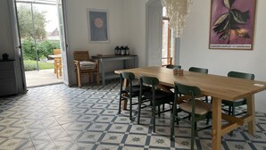 A dining area with a wooden table and chairs, a chandelier, and a framed artwork on the wall.