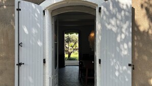 An open arched doorway leading to a tiled interior space with a view of greenery outside.