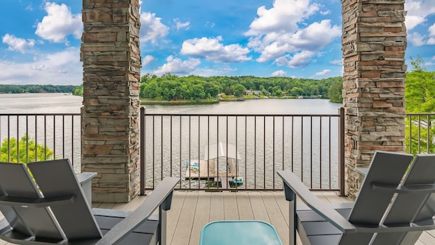 A balcony with stone pillars, a view of a lake, and lounge chairs. - Expansive Retreat with Heated Pool & Gorgeous Views (Cullman)